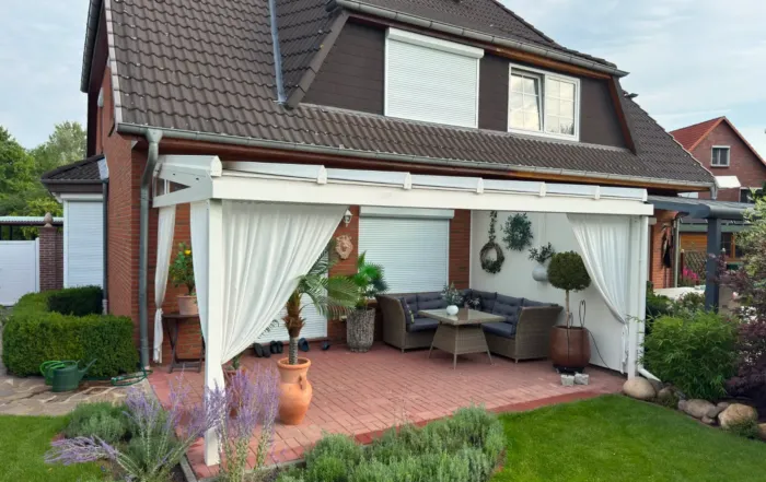 Moderne Glas-Terrassenüberdachung in gepflegtem Garten